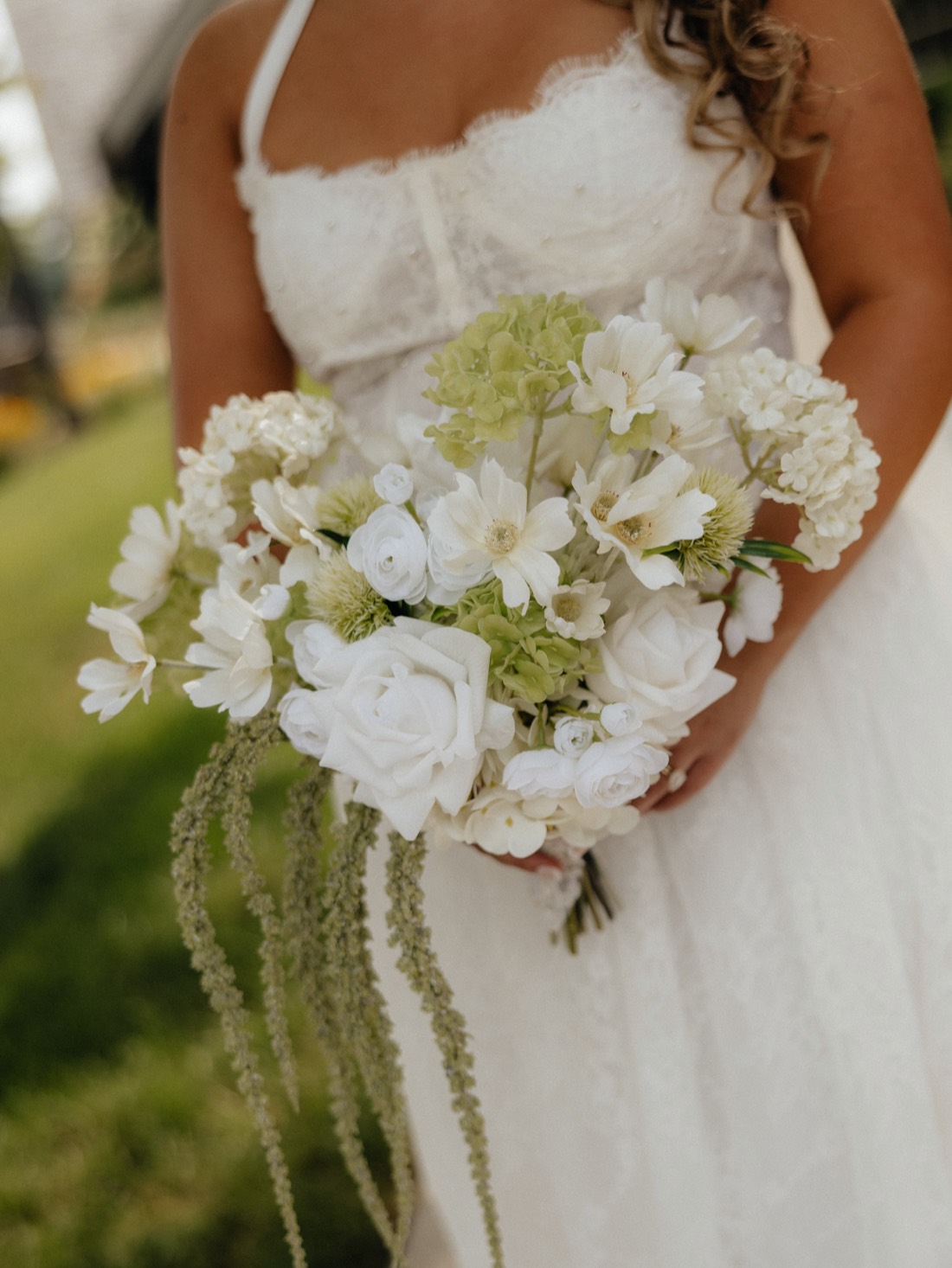 A bride holding a white and green bouquet with trailing amaranthus