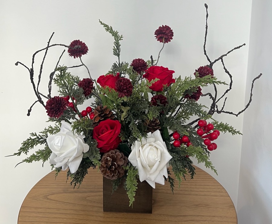 Standard winter arrangement: red and white roses, pine, berries, pinecones and bare branches in a wooden box